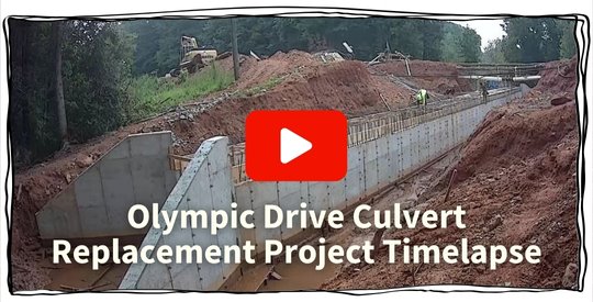 Olympic Drive culvert during repairs showing a concrete culvert surrounded by dirt and construction debris.