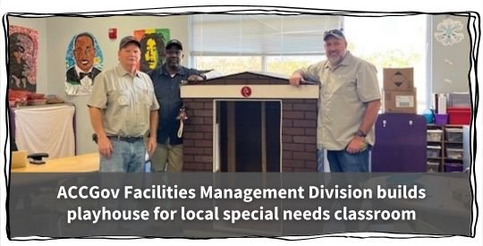 Staff members Johnny Wiley, Ron Harris, and Corey Weaver (L to R) stand in front of a playhouse in a classroom