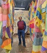 Jamele Wright, Sr. stands between fabrics art works