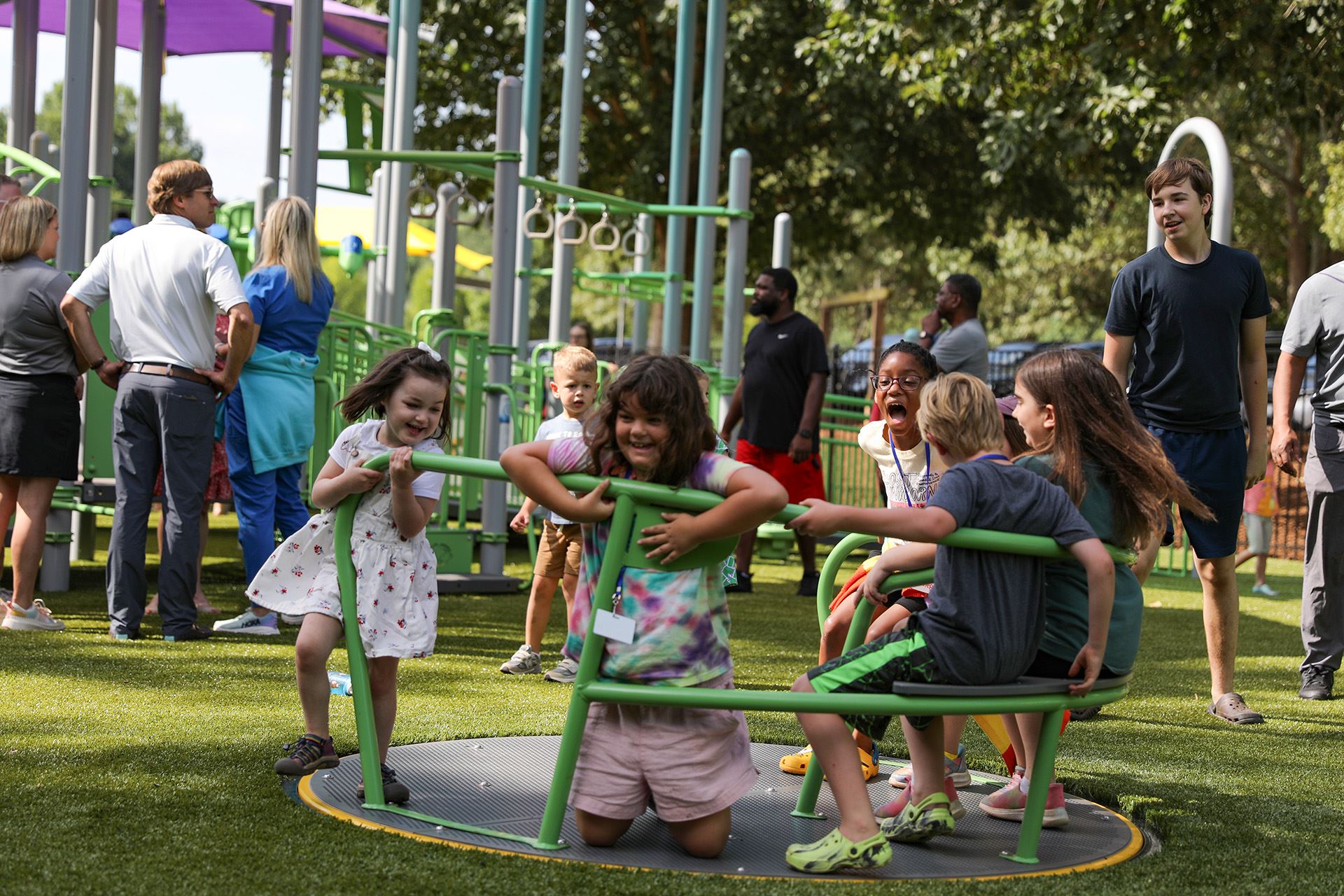 Several children enjoying a merry-go-round built at grade.
