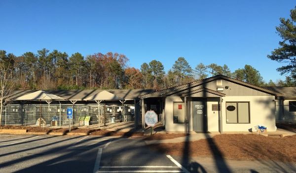 Animal Shelter building on other side of crosswalk with fences in front and trees behind.