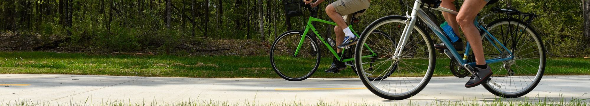 Two bikes ride the paved Greenway Trail. 