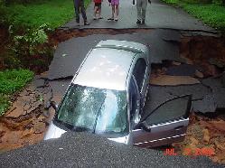 Washed out street with car in hole